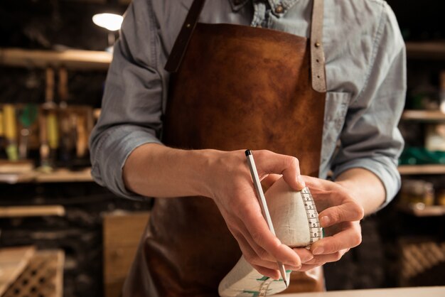 Bijgesneden afbeelding van een schoenmaker die een schoen meet