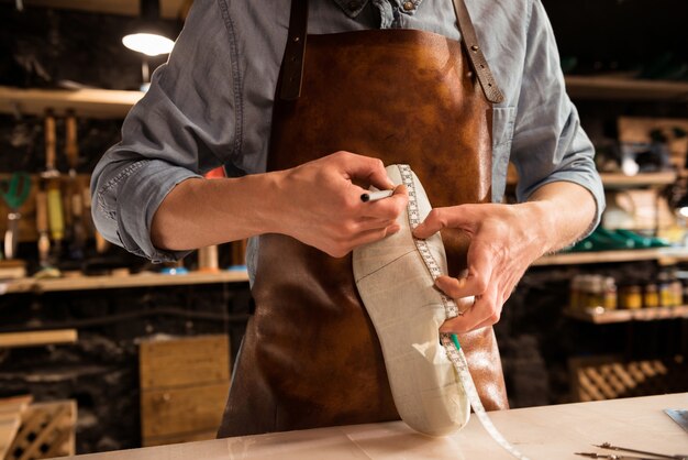 Bijgesneden afbeelding van een schoenmaker die een schoen meet