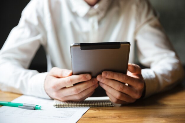 Bijgesneden foto van man in wit overhemd met behulp van digitale tablet