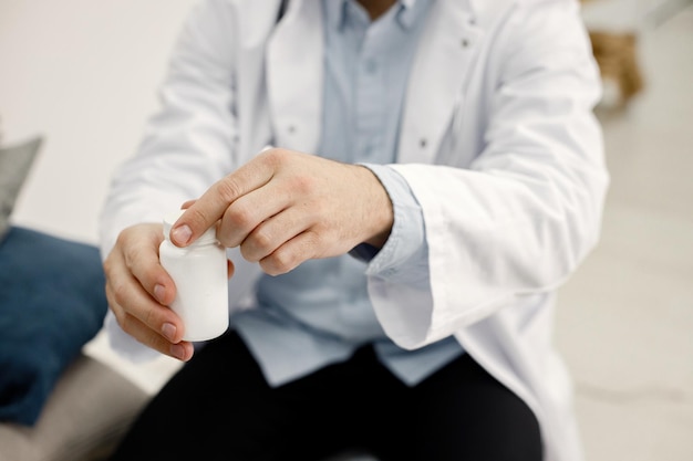 Bijgesneden foto van mannelijke kinderarts met pot met medicijnen