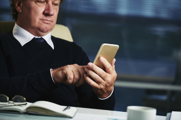 Bijgesneden heer die berichten op zijn smartphone controleert