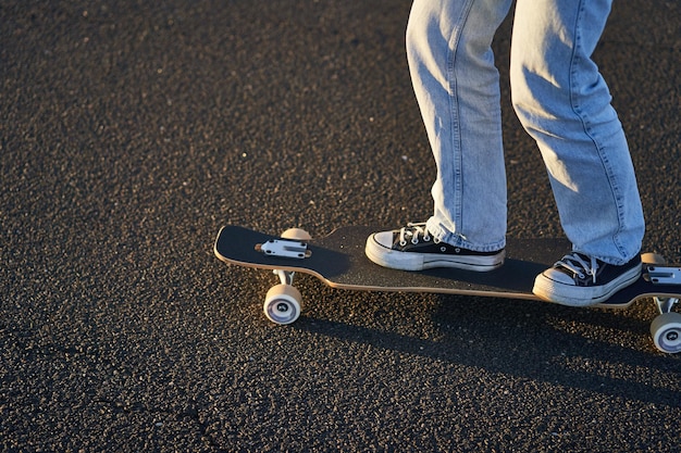 Gratis foto bijgesneden opname van benen op longboard skater meisje rijdt haar skateboard op straat vrouwelijke tiener op cru