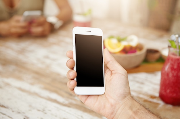 Bijgesneden portret van blanke man surfen op internet op zijn witte slimme telefoon