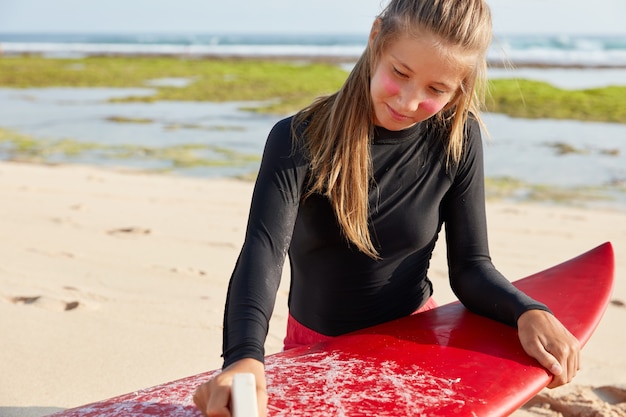 Bijgesneden schot van aantrekkelijke vrouw gebruikt wax voor veilig surfen, heeft een aantrekkelijk uiterlijk