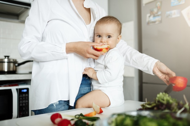 Bijgesneden schot van moeder die babyschijfje appel geeft