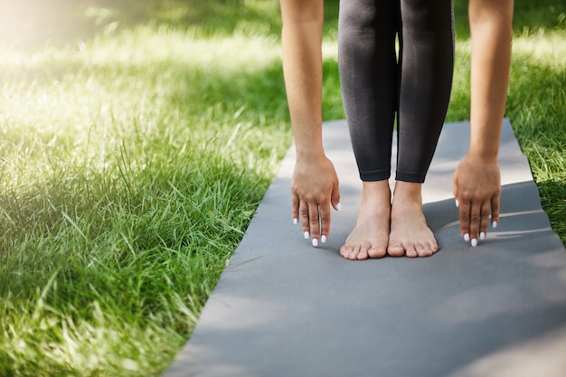 Bijgesneden schot van vrouw doet pilates of yoga of oefeningen in het park. handen en voeten geplant op yogamat.