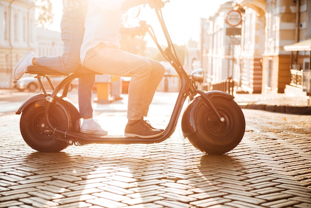 Bijgesneden zijaanzicht van jonge Afrikaanse paar rijdt op modermotor op straat