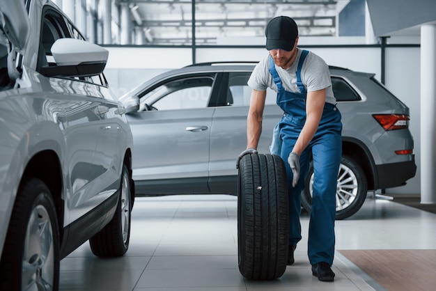 Bijna klaar. Monteur met een band bij de reparatiegarage. Vervanging van winter- en zomerbanden