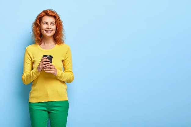 Binnen schot van aangenaam uitziende glimlachende vrouw met rood golvend haar