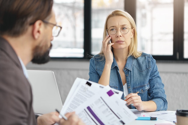 Binnen schot van blonde vrouw met zakelijk gesprek met collega