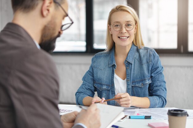 Binnen schot van blonde vrouw met zakelijk gesprek met collega