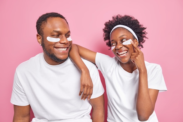 Binnenopname van een gelukkige zorgeloze zwarte vrouw en man kijkt met een glimlach naar elkaar om schoonheidspleisters aan te brengen