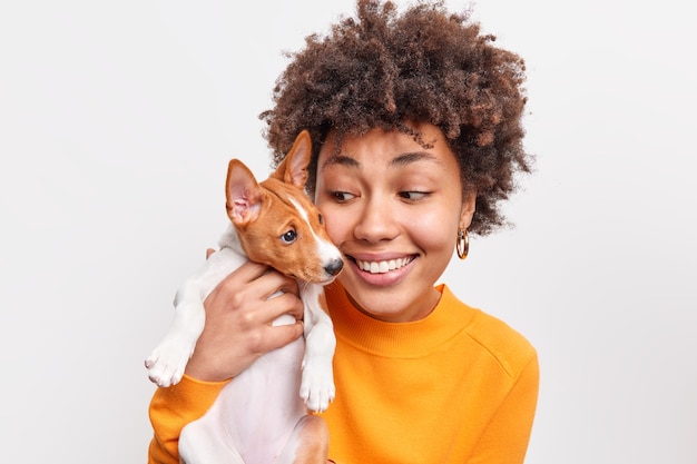 Binnenopname van vriendelijke vrouw en hond die plezier hebben terwijl ze samen spelen, goede relaties hebben, genieten van een goed moment. Positieve vrouwelijke huisdiereneigenaar houdt kleine puppy. Dieren en mensen concept.