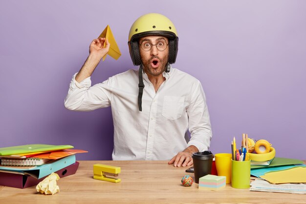 Binnenschot van verbaasde werknemer die aan het bureau zit