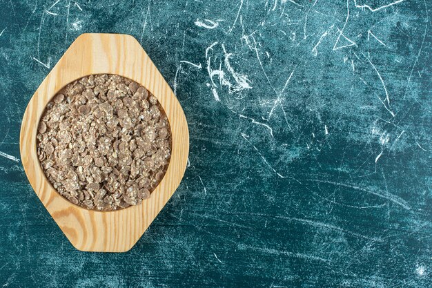 Biologische, zelfgemaakte muesli in een houten bord, op de blauwe achtergrond. Hoge kwaliteit foto