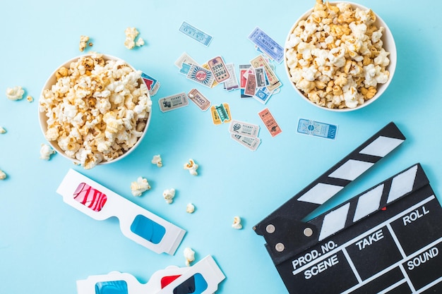 Bioscoop minimaal concept. woordfilm, popcorn, filmklapper, 3d-bril en tickets bovenaanzicht plat op blauwe achtergrond