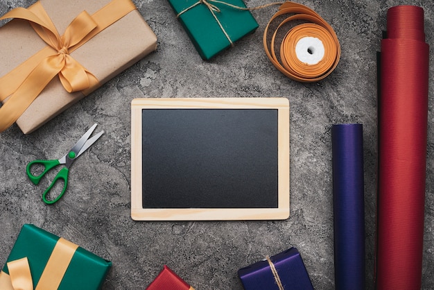 Gratis foto blackboard mock-up op gestructureerde achtergrond met geschenken en inpakpapier