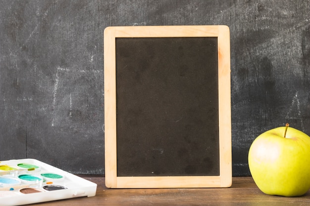 Gratis foto blackboard op tafel met verven en apple