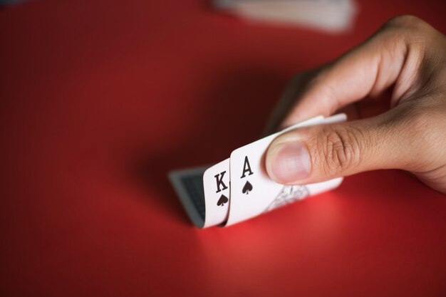 Blackjack kaarten in handen op rode tafel