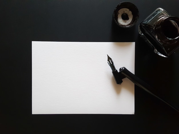 Gratis foto blad papier, pen en inkt van zwart op zwart bureau.
