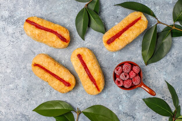 Bladerdeegkoekjes met frambozenjam en bevroren frambozen op licht