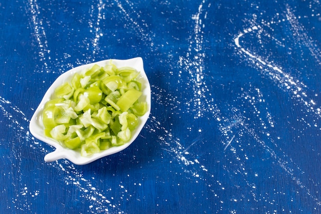 Bladvormige plaat van gesneden groene paprika op marmeren ondergrond.