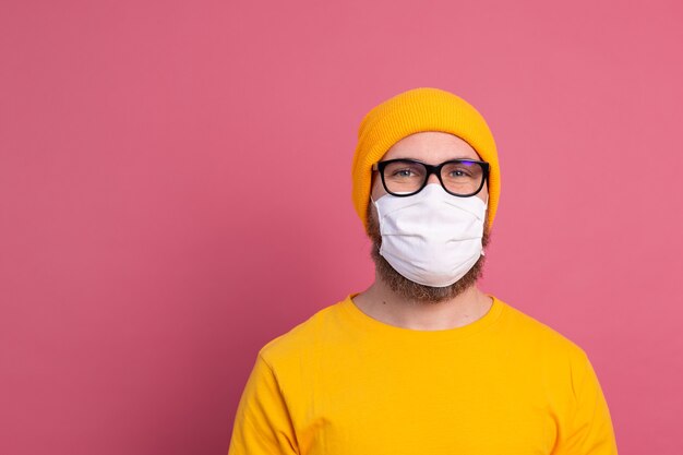 Blanke jonge man in glazen met medisch masker voor eenmalig gebruik om infectie, luchtwegaandoeningen zoals griep te voorkomen