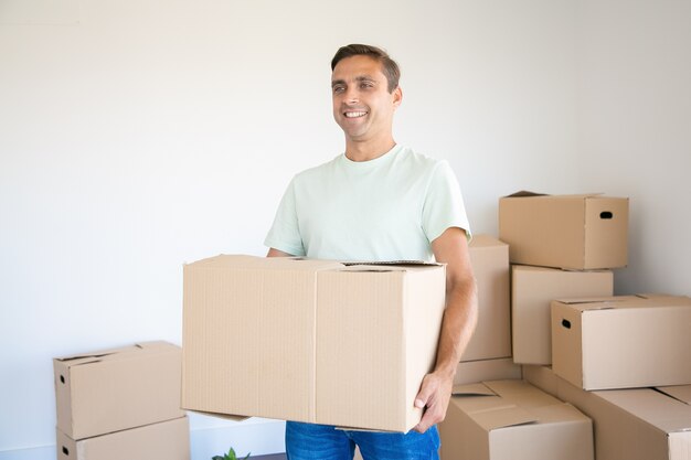 Blanke man met kartonnen doos in zijn nieuwe huis of appartement