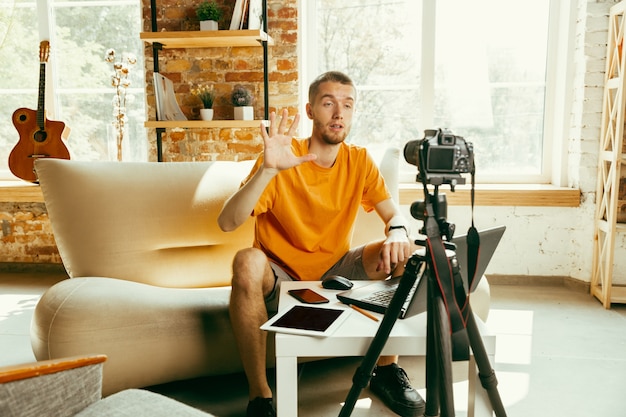 Blanke mannelijke blogger die met camera videoreview van gadgets thuis opneemt