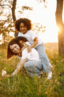 Blanke moeder en twee haar afro-amerikaanse dochters omarmen elkaar buitenshuis