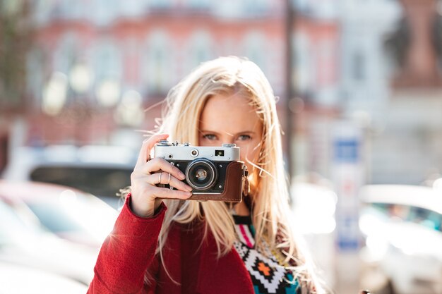 Blanke vrouw buiten lopen. Camera in handen houden.