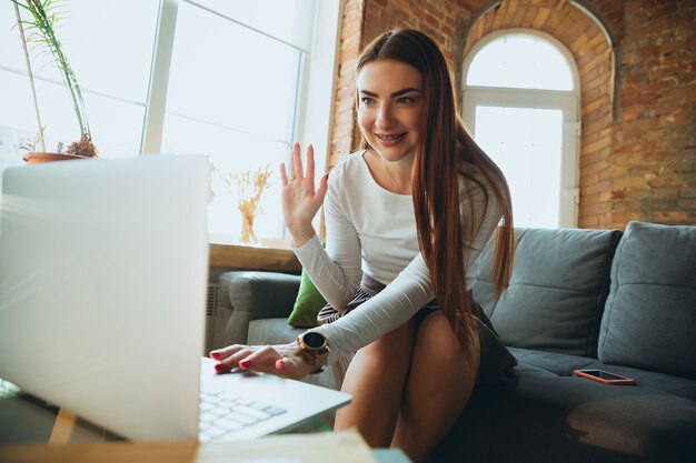 Blanke vrouw zingt tijdens online concert thuis geïsoleerd en in quarantaine geplaatst. Camera gebruiken, laptop, streamen, cursussen opnemen, dansen. Concept van kunst, ondersteuning, muziek, hobby, onderwijs.