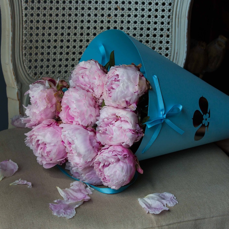 Gratis Foto blauw kartonnen boeket van roze pioenrozen op een stoel.