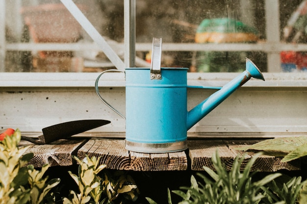 Gratis foto blauwe gieter met troffel op houten tafel