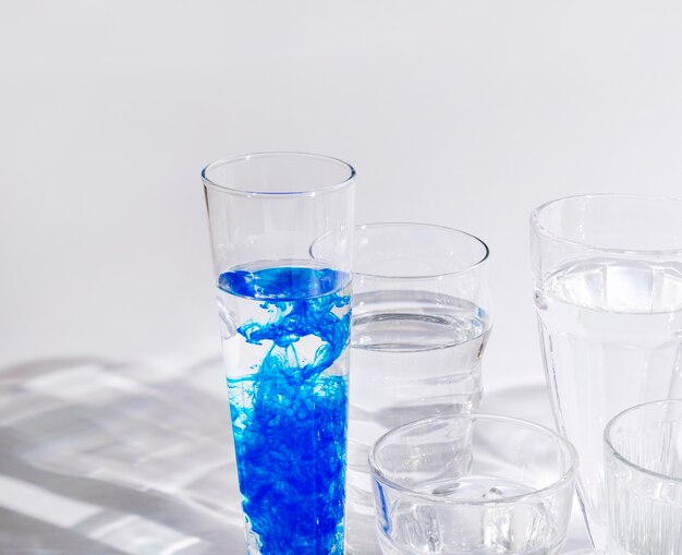 Blauwe inkt opgelost in water in het glas tegen een witte achtergrond