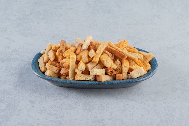 Blauwe kom smakelijke krokante crackers op stenen achtergrond.