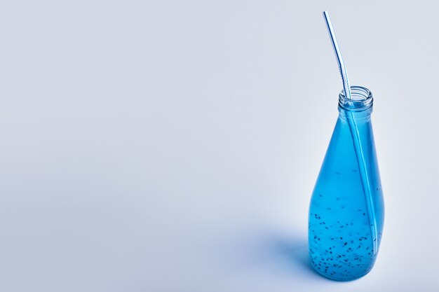 Blauwe minerale drank in een glazen fles.