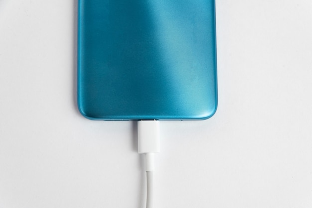 Gratis foto blauwe mobiele telefoon aangesloten op usb-kabel type c - opladen