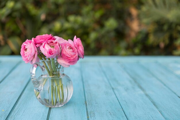 Blauwe oppervlakte met roze bloemen op glazen vaas