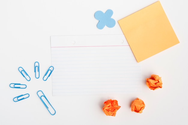 Blauwe paperclip en verfrommeld papier met leeg papier tegen witte achtergrond