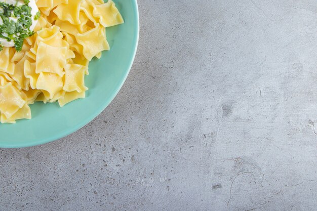 Blauwe plaat van gekookte heerlijke pasta op stenen achtergrond.