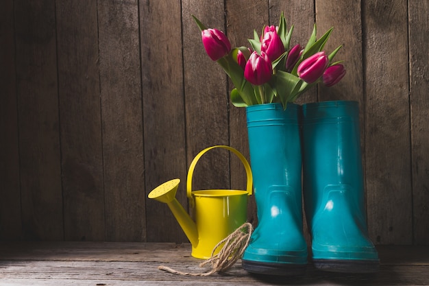 Blauwe plastic laarzen met bloemen en gieter