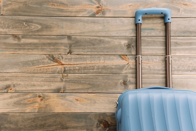 Blauwe reiskoffer tegen houten achtergrond Gratis Foto