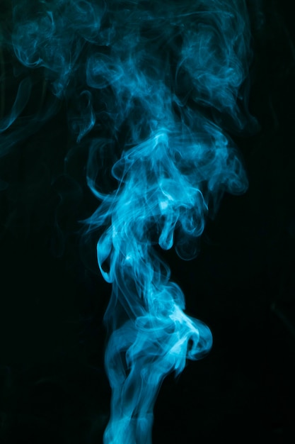 Gratis foto blauwe rook die op zwarte achtergrond wordt uitgespreid