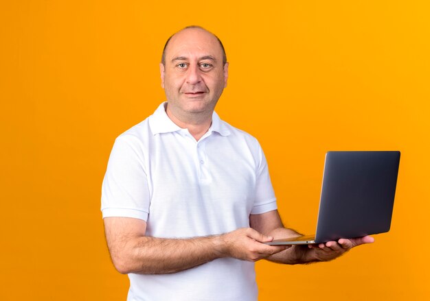 Blij casual volwassen man met laptop geïsoleerd op gele achtergrondkleur