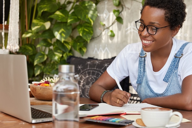 Blij dat een vrouw met een donkere huidskleur online naar webinars kijkt, gericht op de laptop