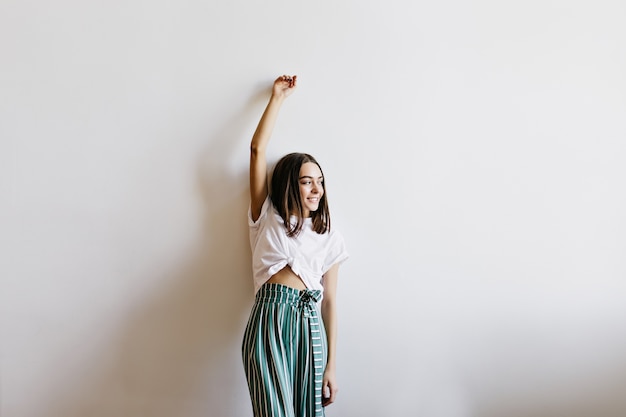 Blij dat jonge vrouw in schattige pyjama's thuis poseren. Indoor foto van lief brunette meisje staan.