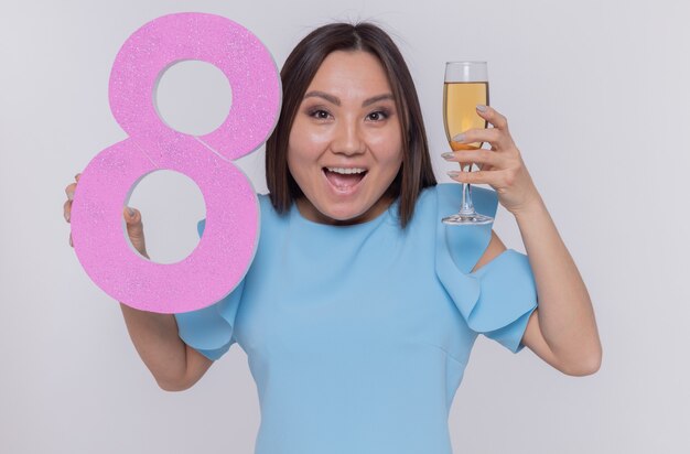 blij en opgewonden Aziatische vrouw met nummer acht en een glas champagne