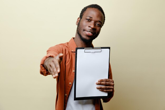 Blij hand in hand naar camera jonge Afro-Amerikaanse man met klembord geïsoleerd op een witte achtergrond
