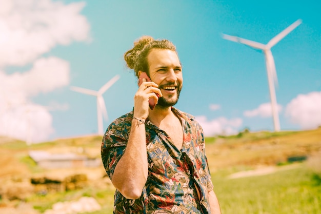 Blij jong mannetje die op mobiele telefoon op aard spreken